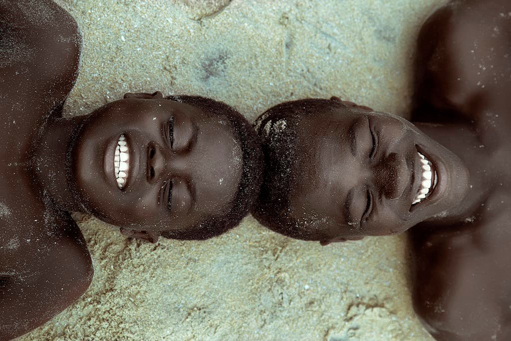 Top View of Two Boys Lying on the Ground with Their Head Touching and Smiling