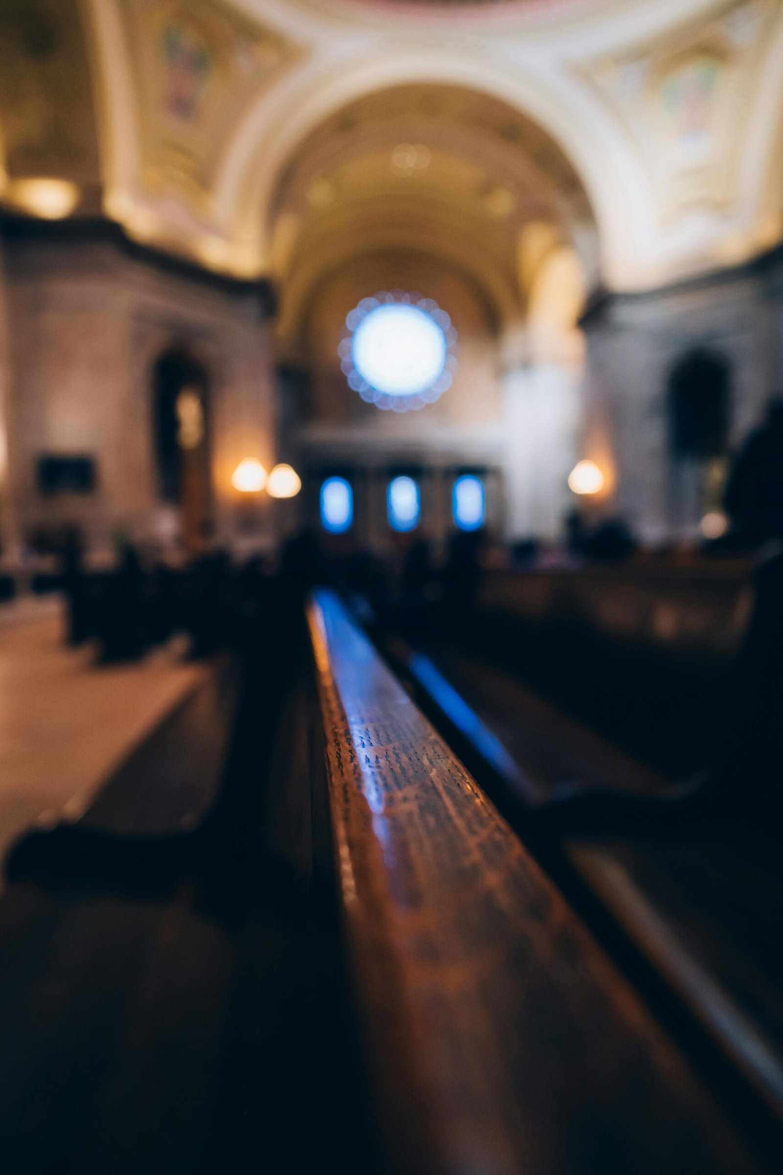Detailed view of a beautifully lit church interior, highlighting wooden benches and architectural arches.