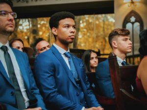 A group of elegantly dressed men sitting at a formal indoor event wearing blue suits.